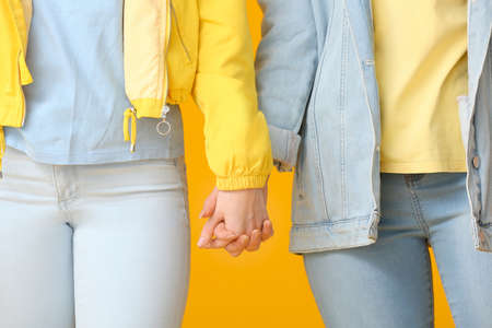 Young lesbian couple holding hands on color backgroundの写真素材