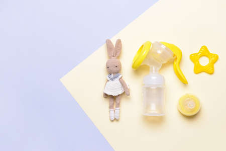 Breast pump and baby accessories on color background