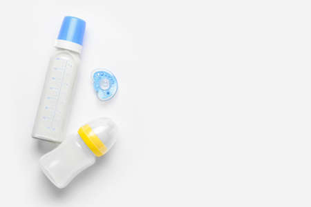Bottles of milk for baby and pacifier on white background