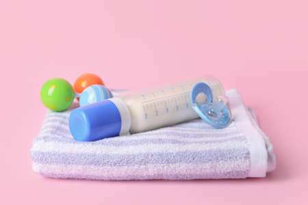 Bottle of milk for baby and accessories on color background