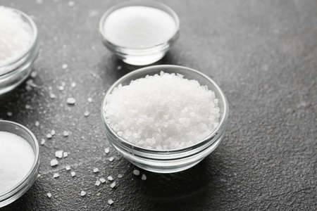 Bowls with salt on dark background