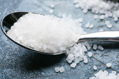 Spoon with salt on color background