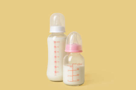 Bottles of milk for baby on color background