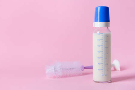 Bottle of milk for baby and brush on color background
