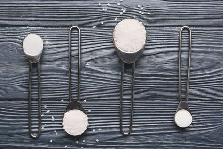 Spoons with salt on dark wooden backgroundの写真素材