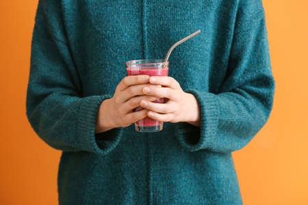 Woman with glass of fruit smoothie on color backgroundの写真素材