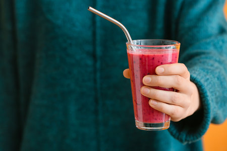 Woman with glass of fruit smoothie on color backgroundの写真素材