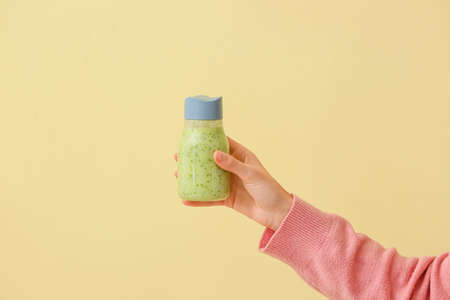 Woman with bottle of fruit smoothie on color backgroundの写真素材