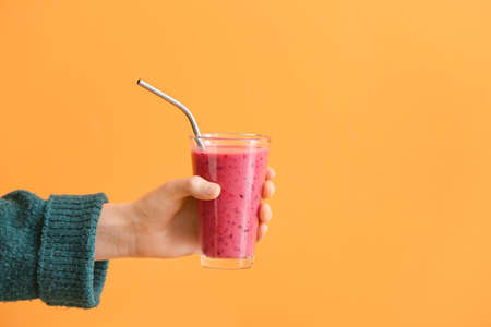 Woman with glass of fruit smoothie on color backgroundの写真素材