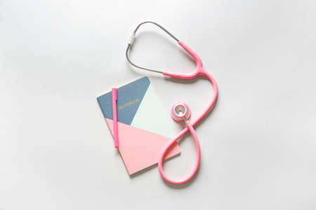 Modern stethoscope, notebook and pen on light backgroundの写真素材