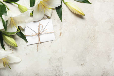 Beautiful lily flowers and letter on light background