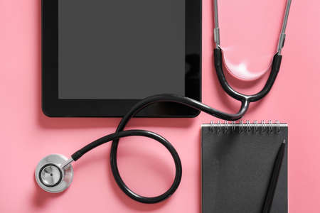 Stethoscope, notebook, tablet computer and pen on color background, closeupの写真素材