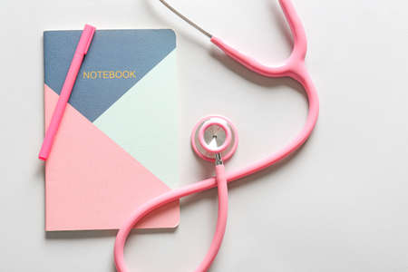Modern stethoscope, notebook and pen on light backgroundの写真素材