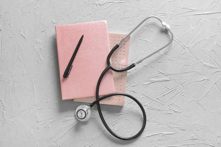 Modern stethoscope, notebooks and pen on gray backgroundの写真素材