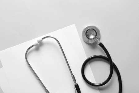 Modern stethoscope and sheets of paper on light backgroundの写真素材