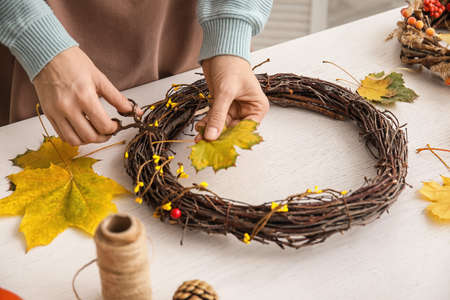 Florist making beautiful autumn wreath at tableの写真素材