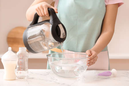 Woman cleaning baby bottle at home