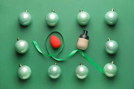 Christmas balls and makeup cosmetics on color backgroundの写真素材