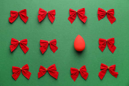 Christmas bows and makeup sponge on color backgroundの写真素材