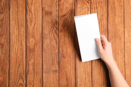 Hand with blank brochure on wooden backgroundの写真素材