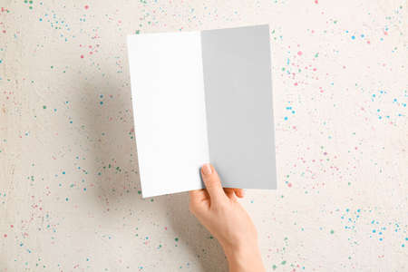 Hand with blank brochure on light background