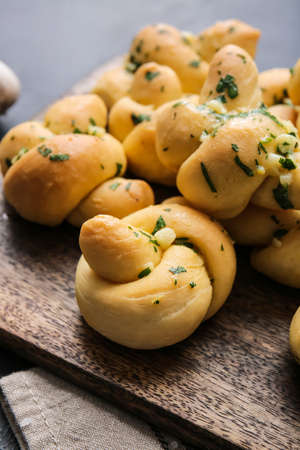 Board with tasty garlic buns on dark background, closeupの写真素材