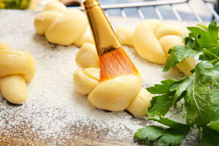 Greasing uncooked garlic buns with oil on color background, closeupの写真素材
