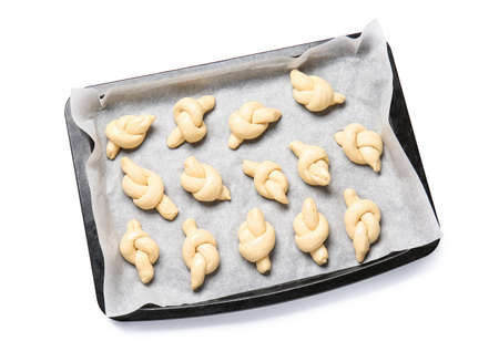 Baking sheet with uncooked garlic buns on white background