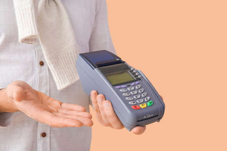 Man with payment terminal on color background, closeup
