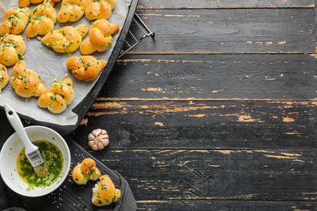 Baking sheet with tasty garlic buns on dark wooden backgroundの写真素材