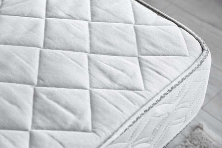 Modern orthopedic mattress on bed in room, closeupの写真素材
