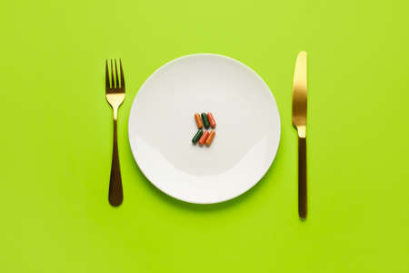 Plate with pills and cutlery on color backgroundの写真素材