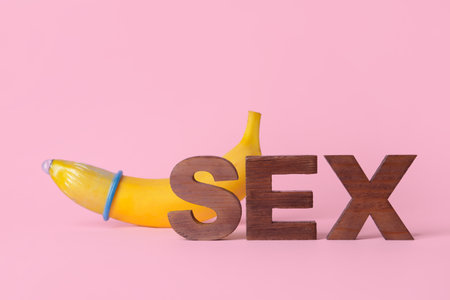 Word SEX and banana in condom on color backgroundの写真素材