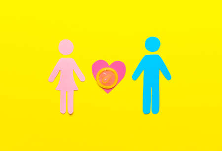 Female and male figures with condom on color background. Erotic conceptの写真素材