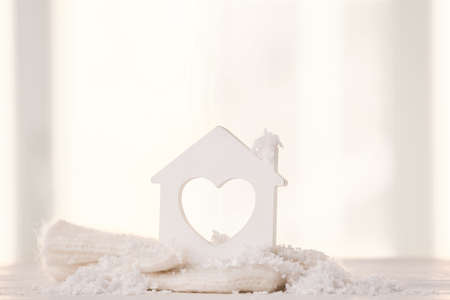 Figure of house, snow and warm mittens on table against light background. Concept of heating seasonの写真素材