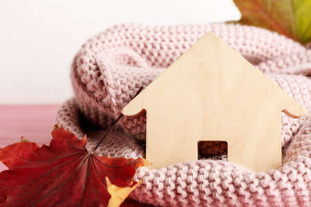 Figure of house, autumn leaves and warm scarf, closeup. Concept of heating seasonの写真素材