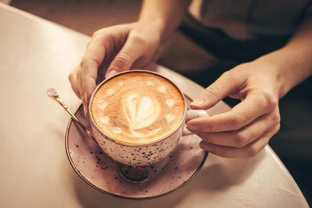 Woman with cup of latte at table in cafe