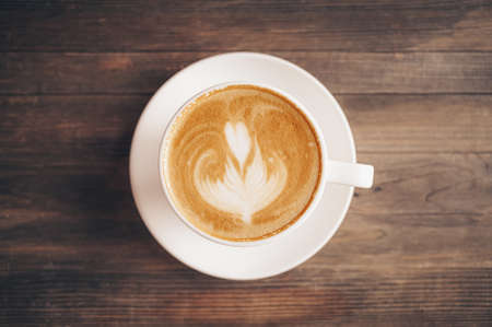 Cup of coffee with latte art on wooden backgroundの写真素材
