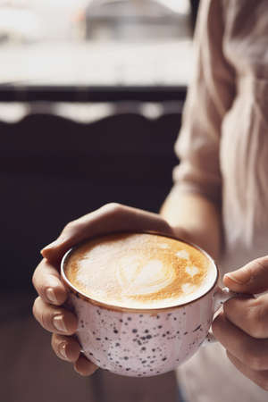 Woman with cup of latte in cafe
