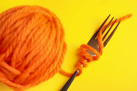 Knitting yarn and fork on color backgroundの写真素材