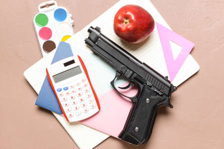 Pistol and stationery on color background. Concept of school shootingの写真素材