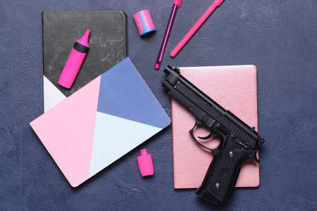 Pistol and stationery on dark background. Concept of school shootingの写真素材