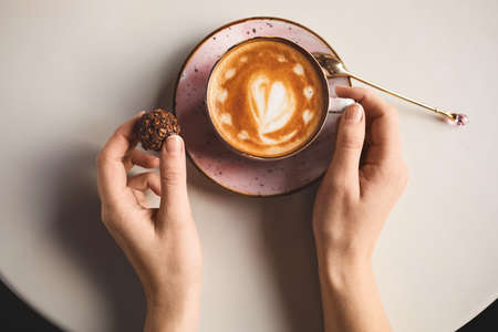 Woman with cup of latte at table in cafeの写真素材
