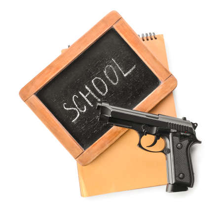 Pistol and chalkboard with notebook on white background. Concept of school shootingの写真素材