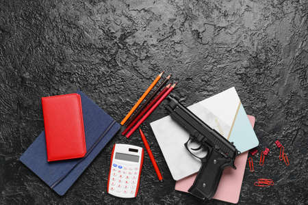 Pistol and stationery on dark background. Concept of school shootingの写真素材