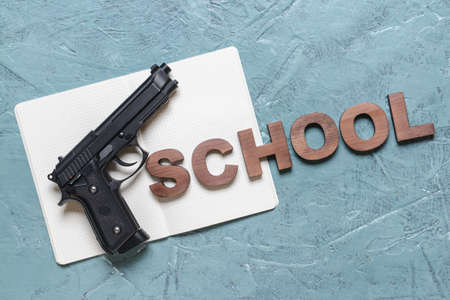 Pistol and notebook on color background. Concept of school shootingの写真素材