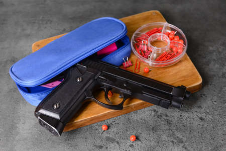 Pistol and stationery on dark background. Concept of school shootingの写真素材