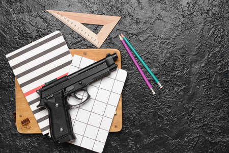 Pistol and stationery on dark background. Concept of school shootingの写真素材
