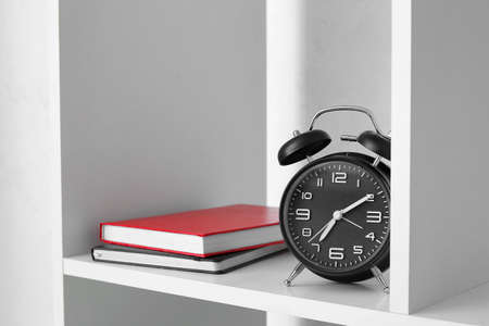 Modern shelf unit with books and alarm clock, closeup
