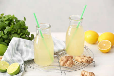 Composition with healthy ginger juice on light wooden background
